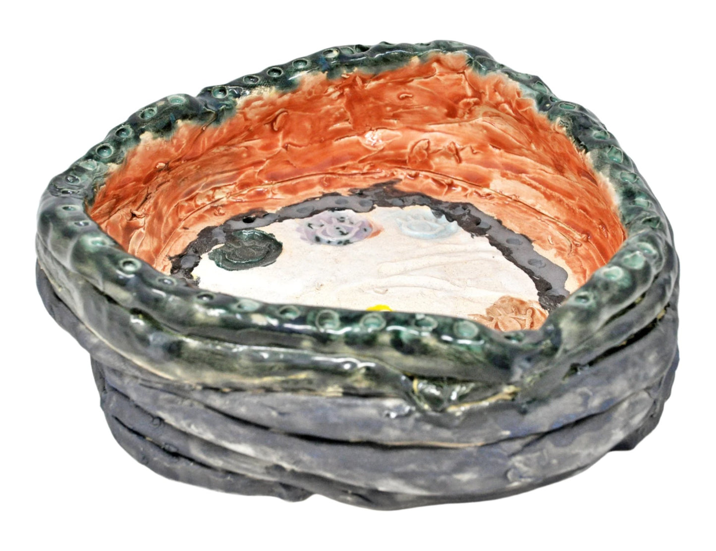 The same ceramic bowl, photographed from the side. Here, the coil technique used to form the walls of the bowl is in focus: stacks of thinly coiled clay  glazed a blueish grey color. The full description of the object is detailed in the previous image. 