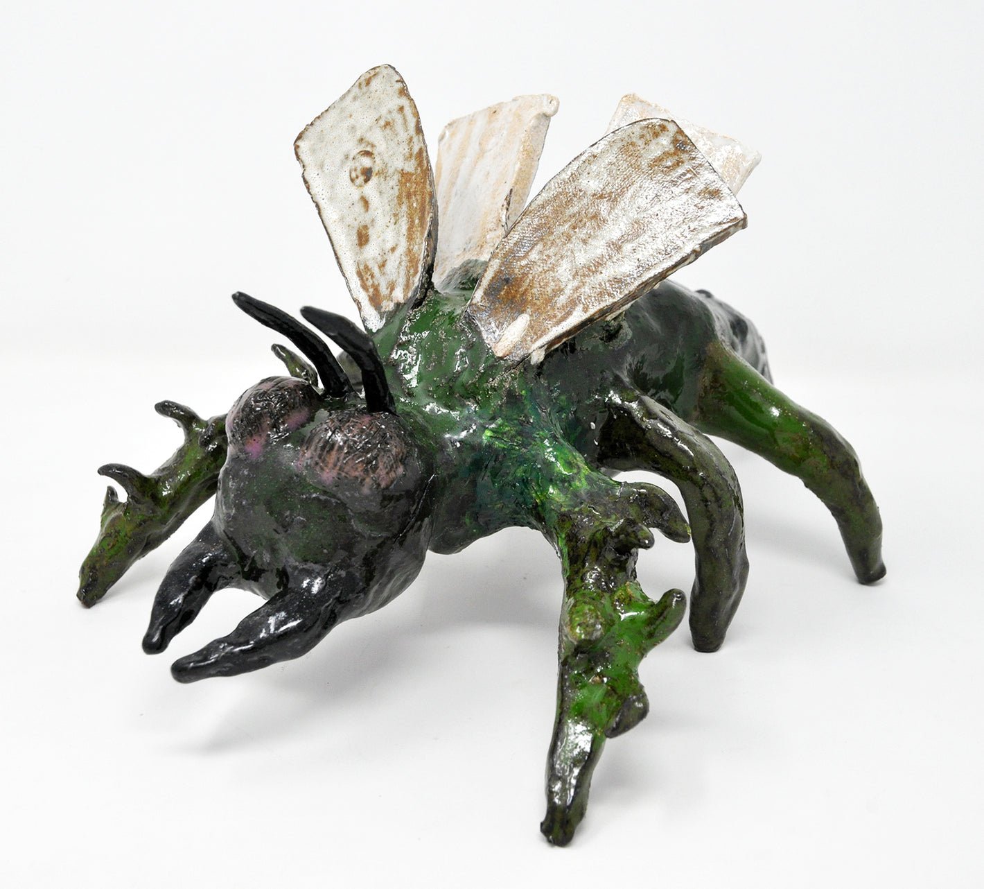 Green and black insect sculpture with six legs, two fangs, and four white wings. 