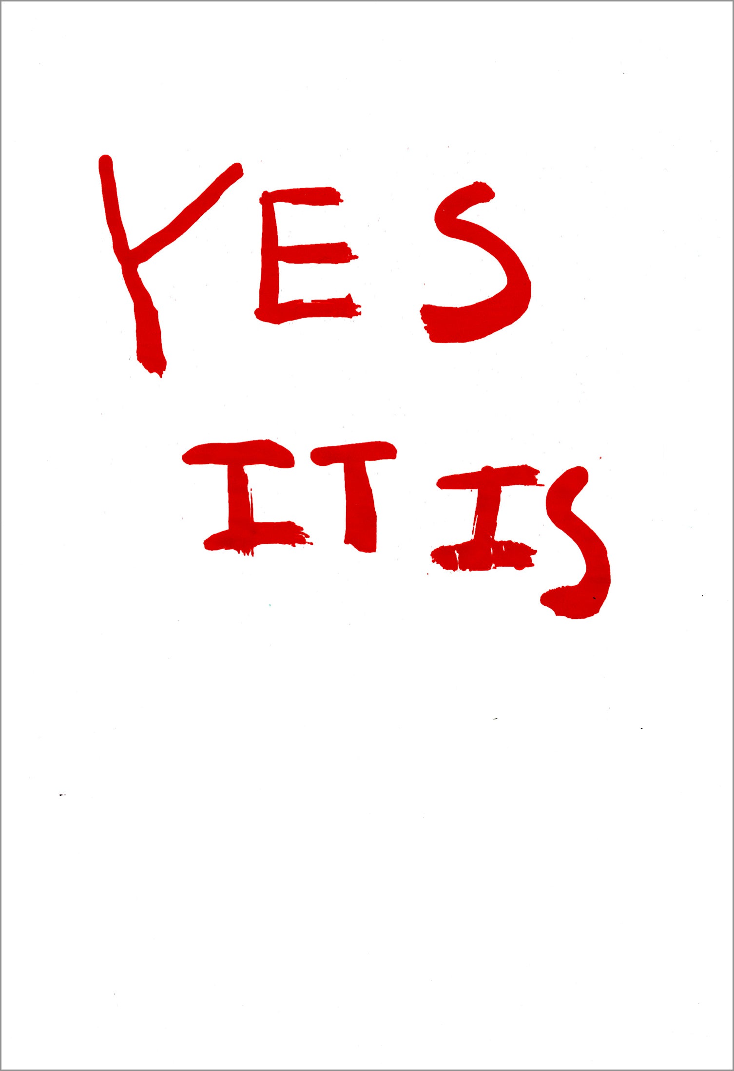 Large red text fills upper half of the surface of a white paper. The text reads "Yes It Is" in all capital letters. 